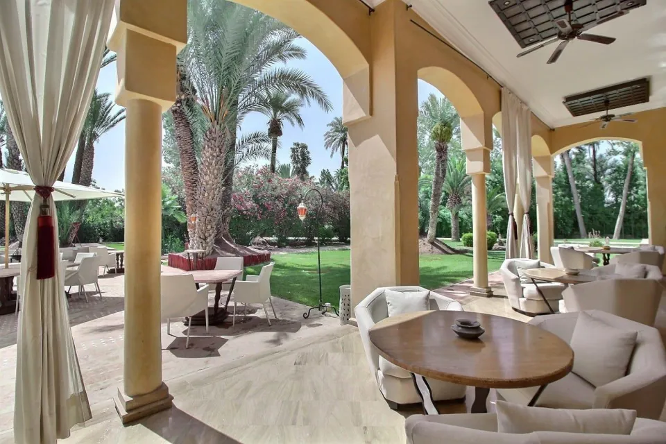 The covered terrace: white armchairs under the arches, opening onto the garden